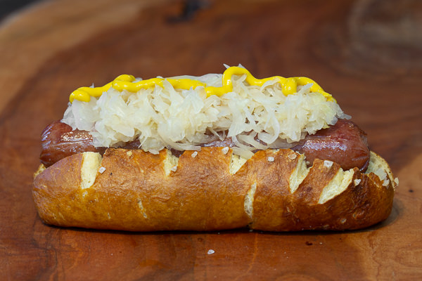 Barvarian soft pretzel bun with hotdog, and sauerkraut after letting dough rise 24 hours and boiled in baked, baking soda.